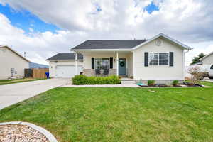 Ranch-style home with covered porch, a garage, fence, a front lawn, and concrete driveway