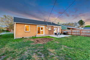 Back of house with fence, a patio, brick siding, entry steps, and a lawn