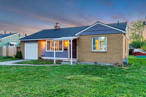 Ranch-style home with a chimney, a lawn, brick siding, fence, and an attached garage