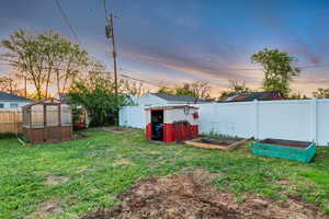 View of yard with an exterior structure, fence, an outbuilding, and a vegetable garden