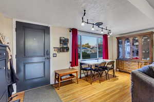 Dining space with light wood-style floors and track lighting