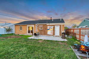 Rear view of house featuring a fenced backyard, entry steps, a yard, and a fire pit