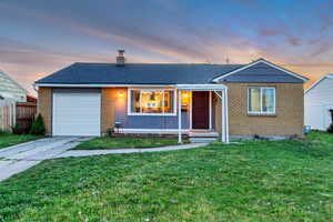 Ranch-style home featuring a garage, fence, a chimney, brick siding, and driveway