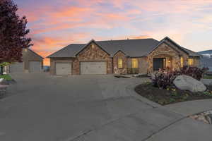 French country home featuring a garage, stone siding, and concrete driveway