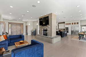 Living area featuring recessed lighting, light wood-style floors, a brick fireplace, and a wealth of natural light