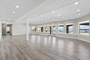 Unfurnished living room with baseboards, plenty of natural light, light wood-type flooring, and recessed lighting