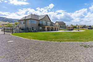 Back of property featuring a yard, a gazebo, fence, and stucco siding