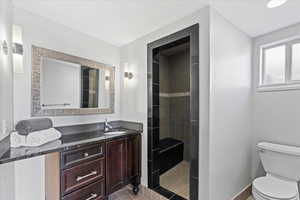 Bathroom with vanity, toilet, and tiled shower