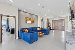 Living room with arched walkways, recessed lighting, and light wood-style flooring