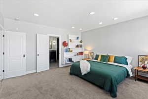 Carpeted bedroom featuring baseboards, recessed lighting, and ensuite bath