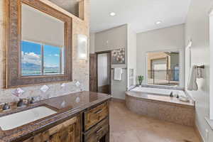 Bathroom featuring vanity, tasteful backsplash, a garden tub, and tile patterned floors