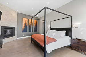 Bedroom with recessed lighting, a large fireplace, and wood finished floors