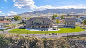 Rear view of house with a residential view, a patio area, a mountain view, a fenced backyard, and a yard