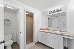 Full bath with vanity, tile patterned floors, toilet, and a shower stall