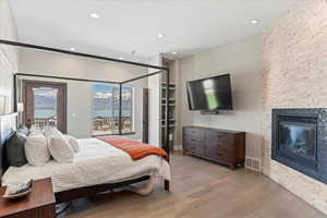 Bedroom featuring visible vents, a fireplace, wood finished floors, access to outside, and recessed lighting
