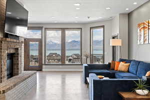Living room with a brick fireplace, recessed lighting, wood finished floors, and a water and mountain view