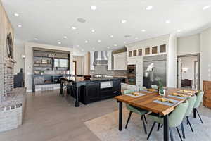 Dining area featuring a brick fireplace, recessed lighting, light wood-style flooring, and visible vents