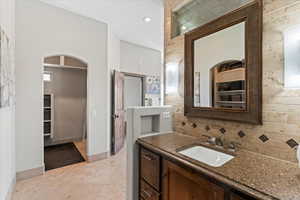 Full bathroom with tasteful backsplash, vanity, baseboards, tile patterned floors, and a spacious closet