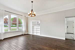 Unfurnished dining area featuring baseboards, dark wood-style flooring, and a chandelier