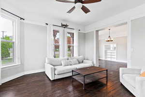 Living room with baseboards, ceiling fan with notable chandelier, and hardwood / wood-style floors