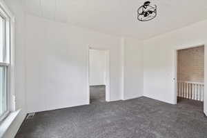 Unfurnished room with carpet floors, plenty of natural light, and visible vents