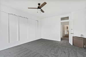 Interior space featuring dark colored carpet and a ceiling fan