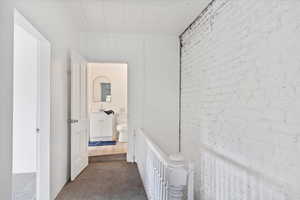 Hallway with a sink, dark carpet, and an upstairs landing