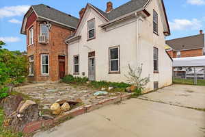 Rear view of house with fence, stucco siding, a chimney, and roof with shingles