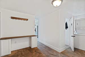 Entryway with stacked washer and dryer, baseboards, and a textured ceiling