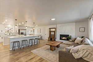Living room with recessed lighting, light wood finished floors, and a fireplace