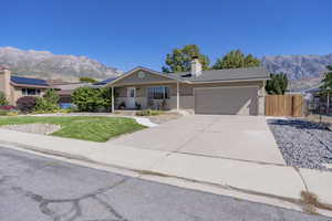 Single story home featuring an attached garage, fence, a mountain view, and a front yard
