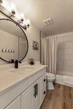 Full bath featuring visible vents, wood finished floors, toilet, and vanity