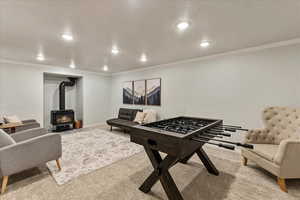Rec room featuring a wood stove, carpet floors, baseboards, ornamental molding, and recessed lighting