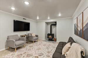 Carpeted living area featuring recessed lighting, baseboards, visible vents, and a wood stove