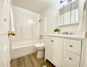 Bathroom with shower / bathtub combination, vanity, toilet, and wood finished floors
