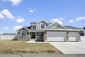 Craftsman-style house with fence, covered porch, board and batten siding, and stone siding
