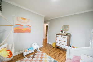 Bedroom featuring crown molding, baseboards, and wood finished floors