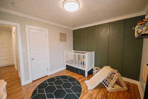 Bedroom with baseboards, ornamental molding, and wood finished floors