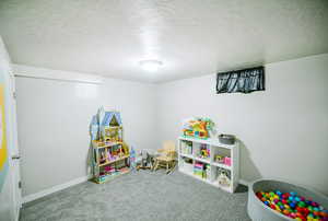 Game room with carpet floors, a textured ceiling, and baseboards
