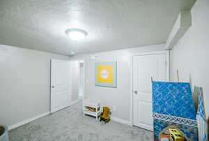 Playroom with carpet floors, a textured ceiling, baseboards, and visible vents