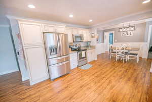 Kitchen featuring crown molding, appliances with stainless steel finishes, recessed lighting, and light wood-type flooring