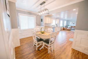 Dining area featuring light wood-type flooring, ornamental molding, a wainscoted wall, and recessed lighting