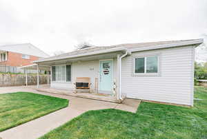 View of front facade with a patio, fence, a shingled roof, and a front yard