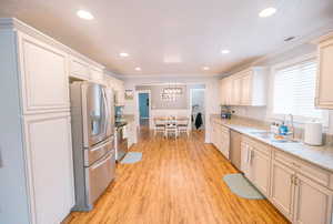 Kitchen featuring ornamental molding, light wood-type flooring, recessed lighting, a sink, and stainless steel appliances