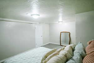 Carpeted bedroom featuring a textured ceiling and baseboards