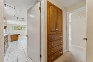 Corridor with baseboards, track lighting, and light tile patterned floors