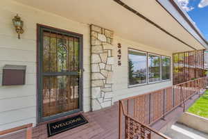 View of exterior entry featuring covered porch and stone siding