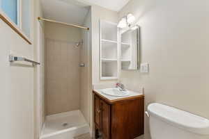 Full bath featuring vanity, toilet, and tiled shower
