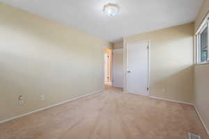 Unfurnished room featuring visible vents, baseboards, and light colored carpet