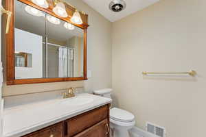 Full bath with tile patterned flooring, vanity, toilet, a shower with shower curtain, and visible vents